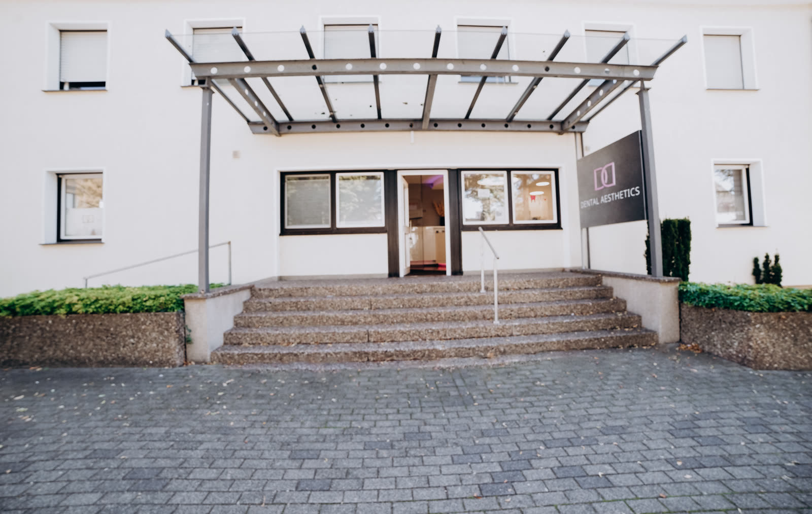 Entrance of the Dental Aesthetics practice at Simonstraße 3 with canopy, steps and practice sign